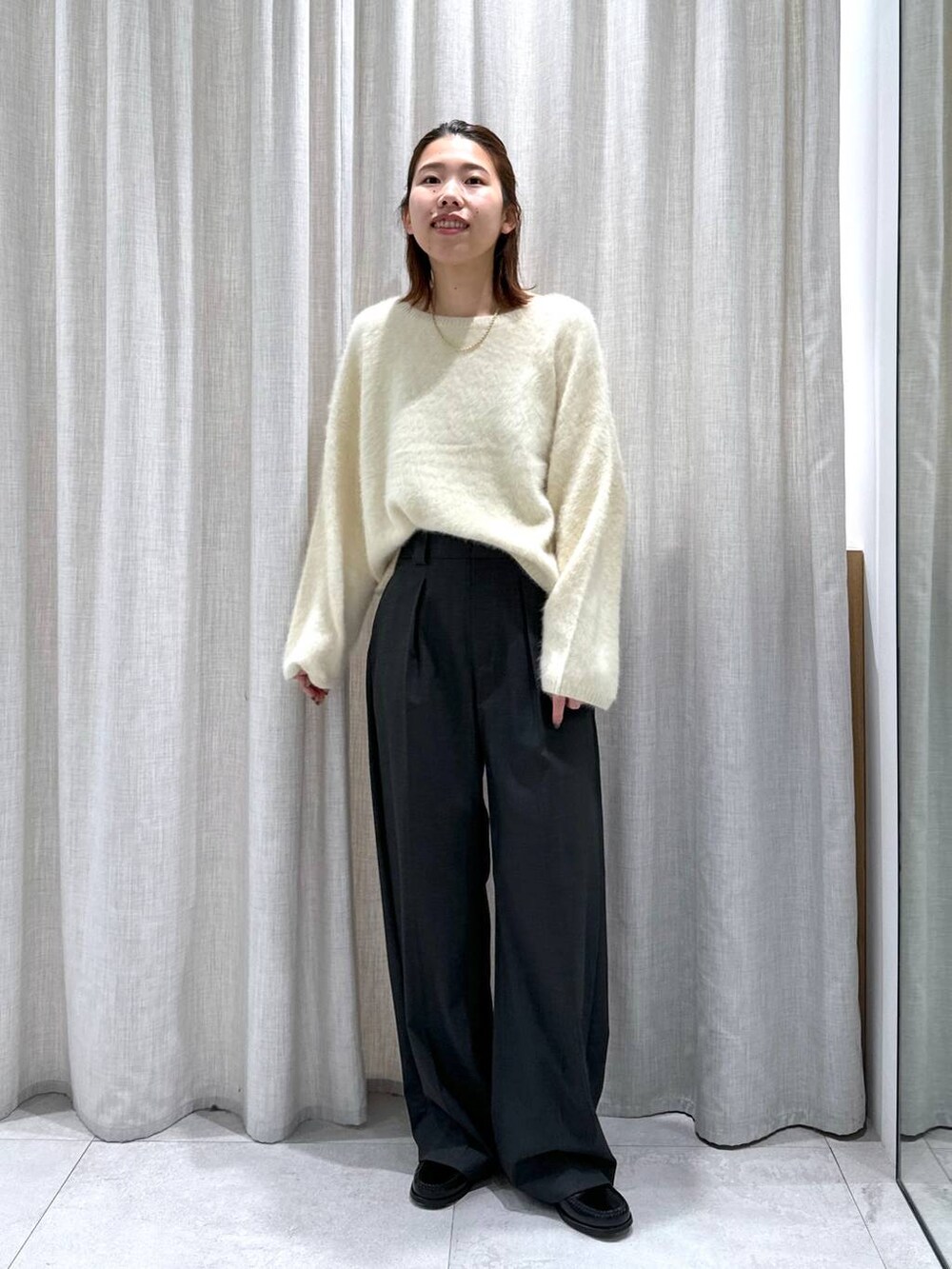 グレー系のスラックス、イエロー系のニット/セーターを着用したレディースの秋コーディネートの4枚目の写真