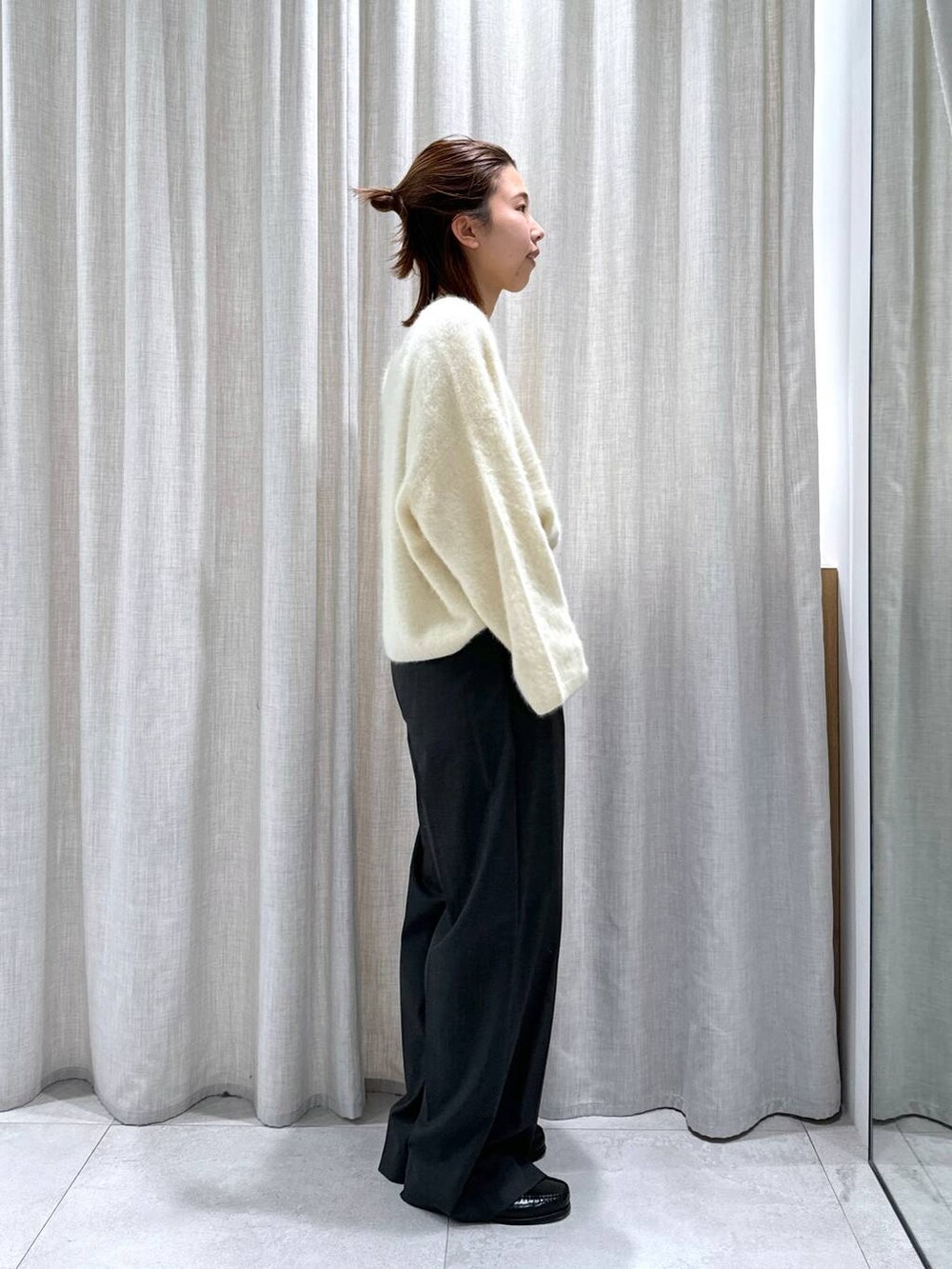 グレー系のスラックス、イエロー系のニット/セーターを着用したレディースの秋コーディネートの5枚目の写真