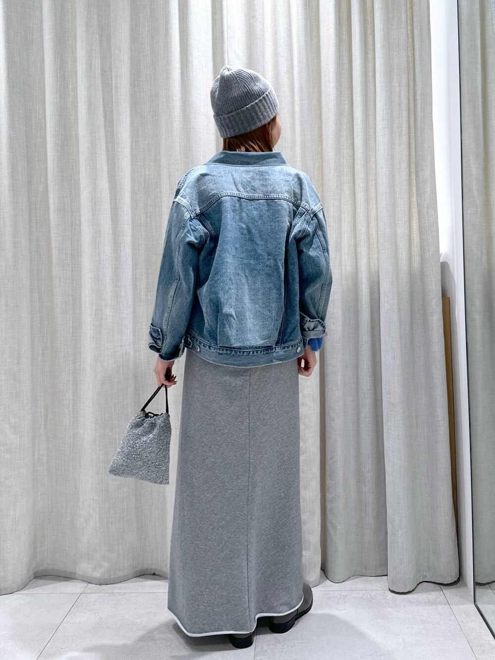 ブルー系のデニムジャケット、ブルー系のニット/セーター、シルバー系のショルダーバッグを着用したレディースの秋コーディネートの5枚目の写真