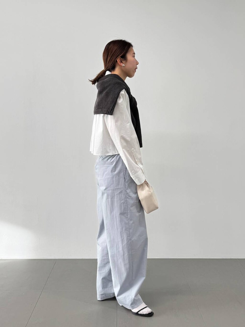 ホワイト系のハンドバッグ、ホワイト系のシャツ/ブラウス、ブラック系のサンダルを着用したレディースの冬コーディネートの5枚目の写真