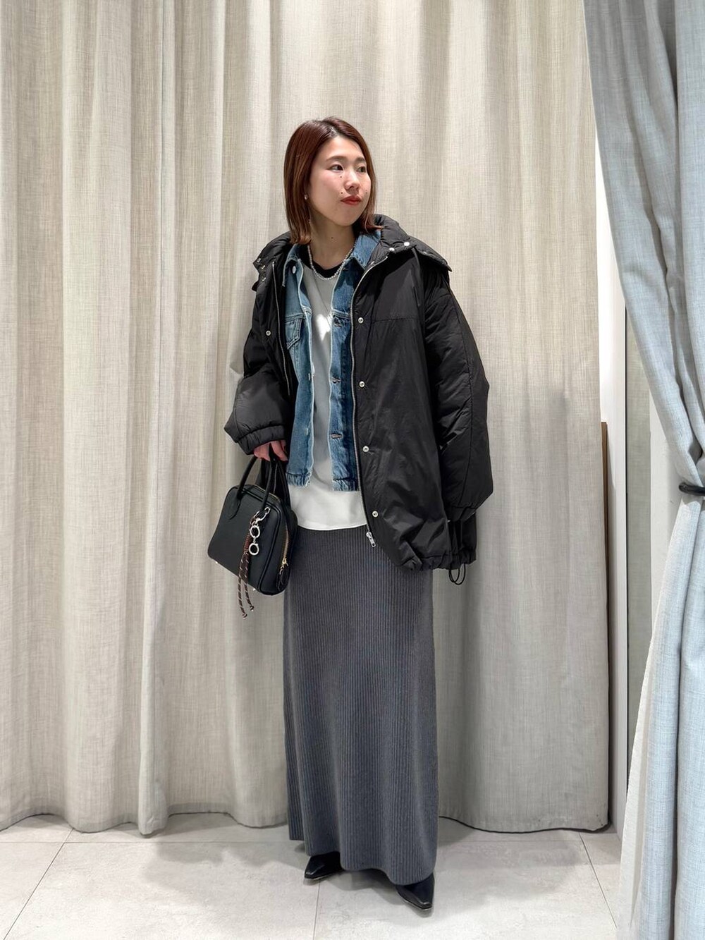 グレー系のブルゾン、ブルー系のTシャツ/カットソー、グレー系のスカートを着用したレディースの冬コーディネートの5枚目の写真