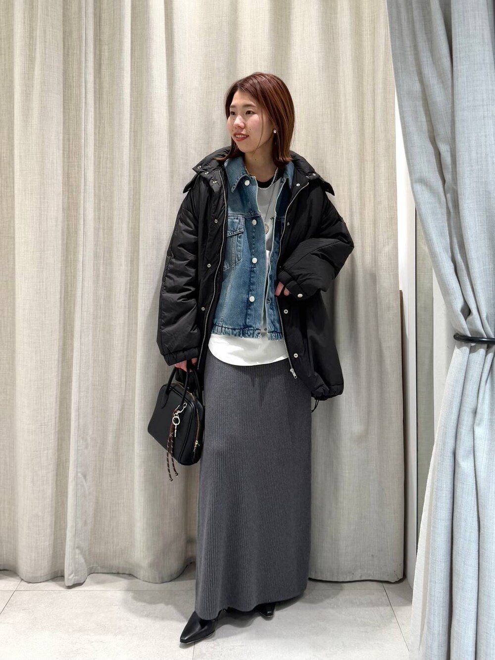 グレー系のブルゾン、ブルー系のTシャツ/カットソー、グレー系のスカートを着用したレディースの冬コーディネートの3枚目の写真