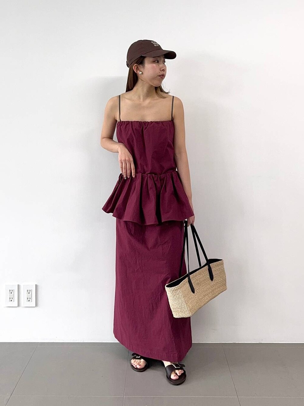 ベージュ系のかごバッグ、レッド系のワンピース、ブラウン系のキャップを着用したレディースの春コーディネートの6枚目の写真