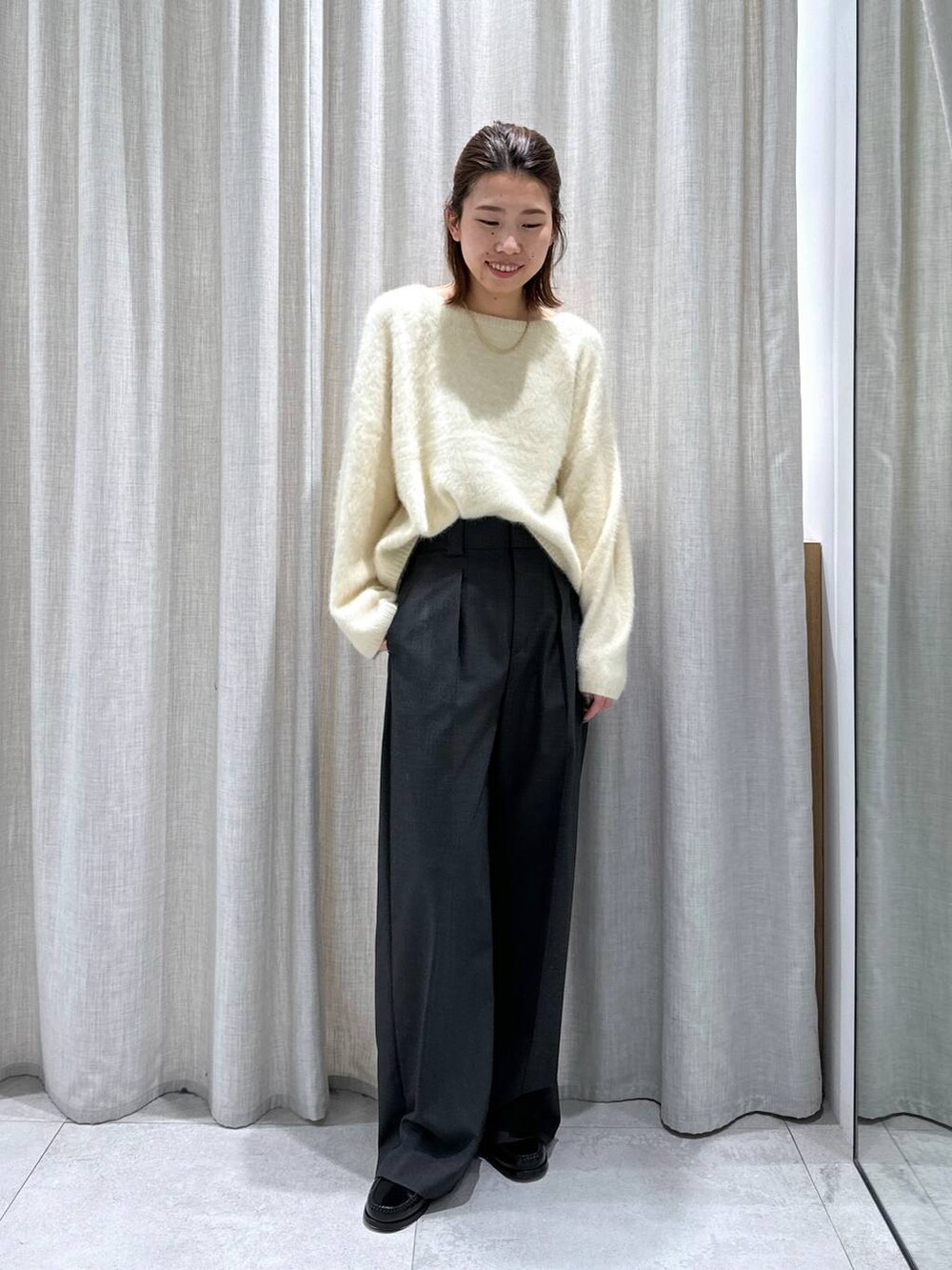 グレー系のスラックス、イエロー系のニット/セーターを着用したレディースの秋コーディネートの3枚目の写真