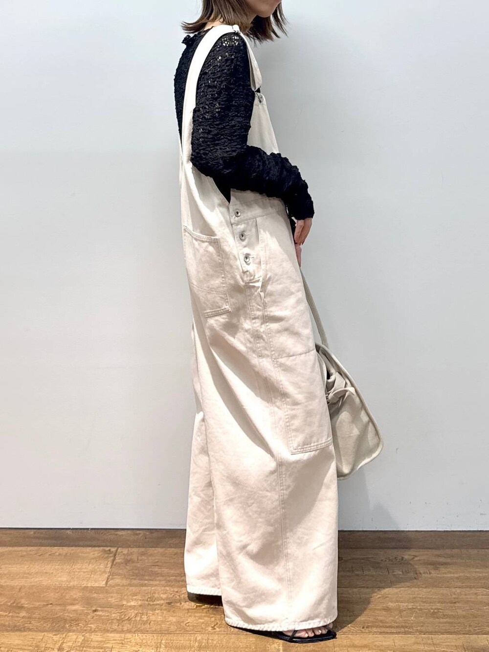 ホワイト系のサロペット/オーバーオール、ブラック系のTシャツ/カットソー、ブラック系のサンダルを着用したレディースの夏コーディネートの4枚目の写真