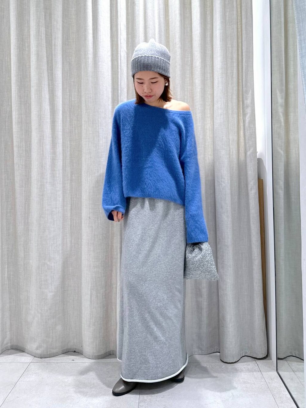ブルー系のニット/セーター、シルバー系のショルダーバッグ、グレー系のスカートを着用したレディースの秋コーディネートの8枚目の写真