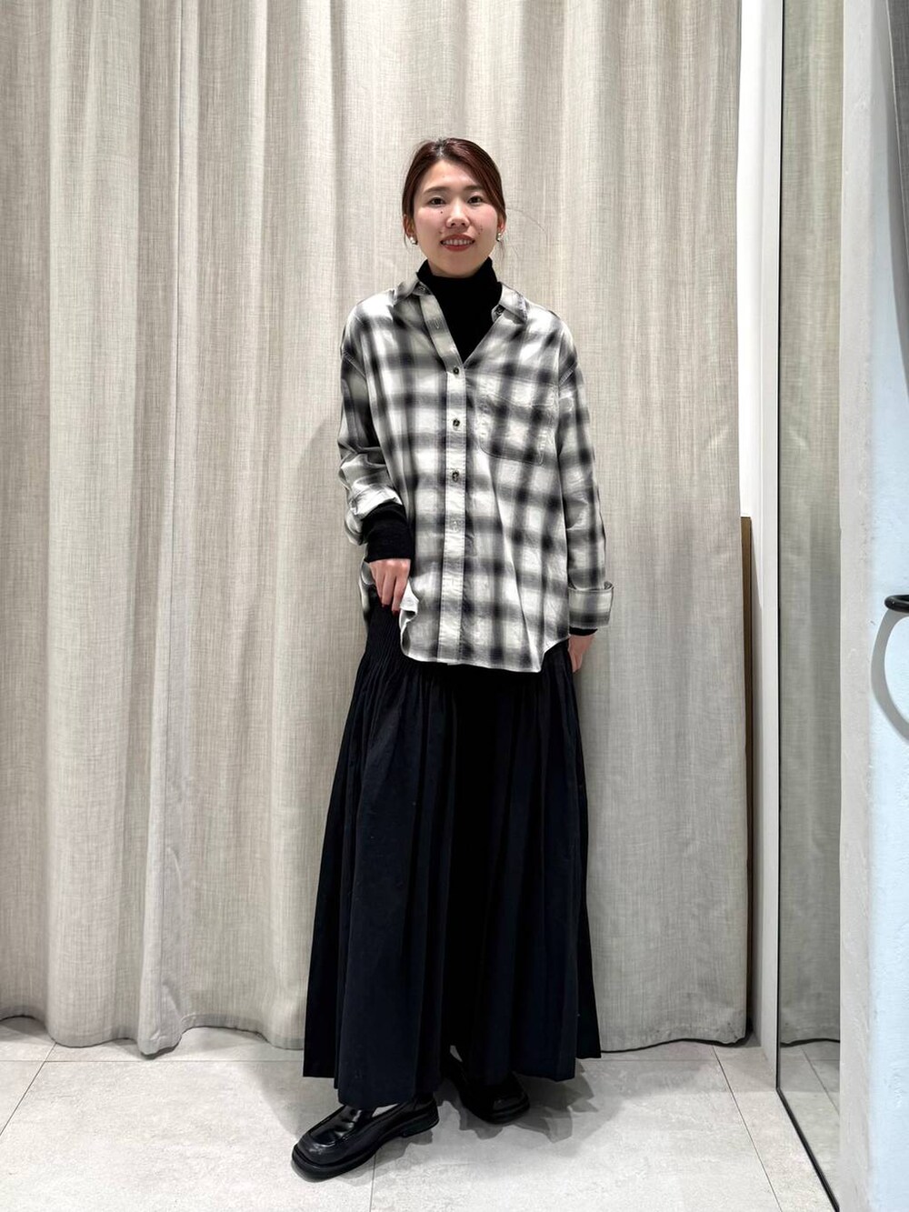 ブラック系のニット/セーター、ブラック系のシャツ/ブラウス、ブラック系のスカートを着用したレディースの冬コーディネートの2枚目の写真