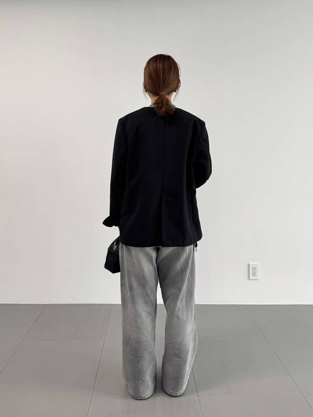 グレー系のデニムパンツ、ブラック系のパンプス、ブラック系のノーカラージャケットを着用したレディースの冬コーディネートの5枚目の写真