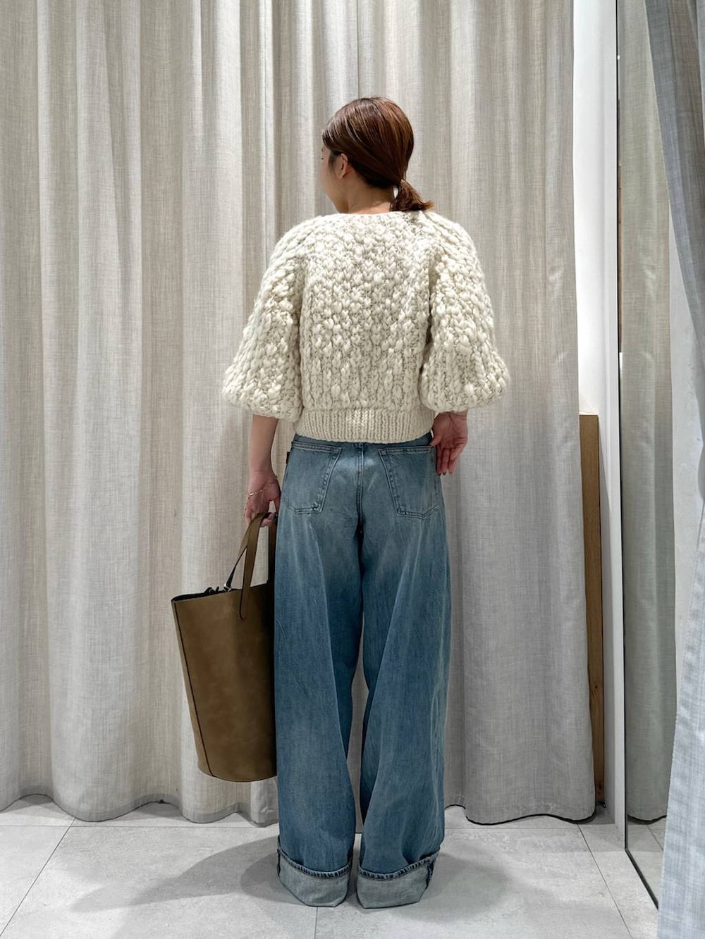 ベージュ系のカーディガン/ボレロ、ブラウン系のサンダル、ブルー系のデニムパンツを着用したレディースの秋コーディネートの4枚目の写真