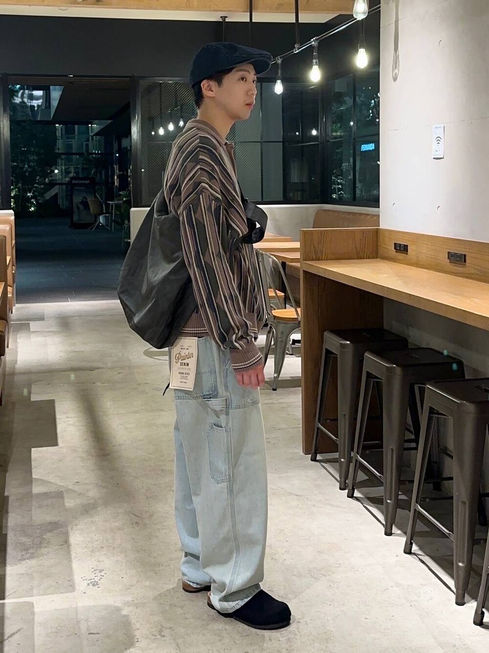 ブルー系のデニムパンツ、ブラック系のショルダーバッグ、ベージュ系のニット/セーターを着用したメンズの秋コーディネートの2枚目の写真