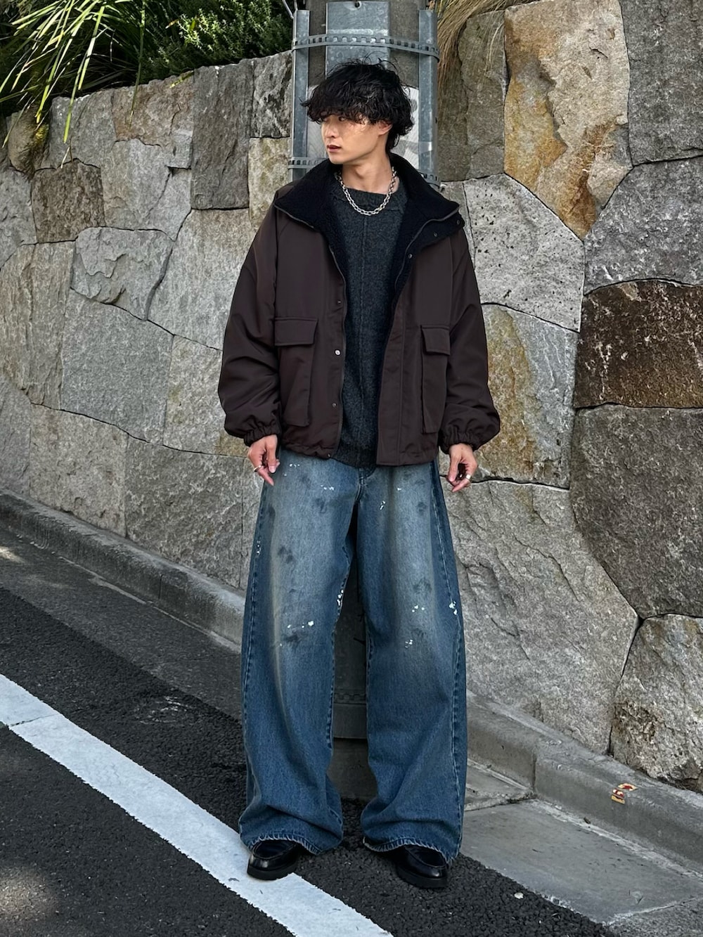 グレー系のニット/セーター、ブラック系のブルゾン、ブルー系のデニムパンツを着用したメンズの冬コーディネートの2枚目の写真