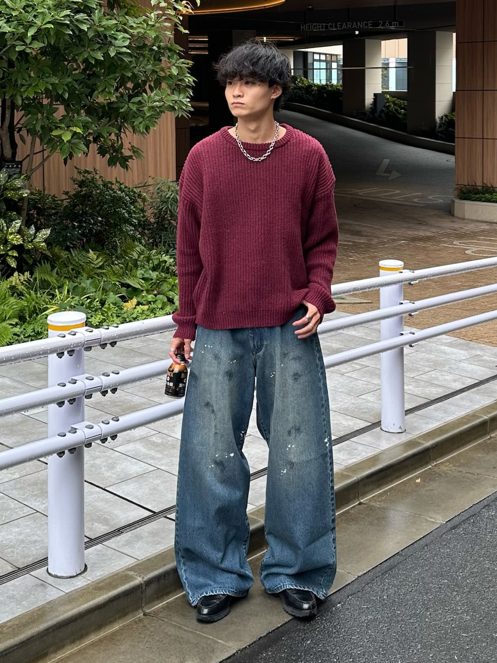 レッド系のニット/セーター、ブルー系のデニムパンツ、ブラック系のローファーを着用したメンズの秋コーディネートの2枚目の写真