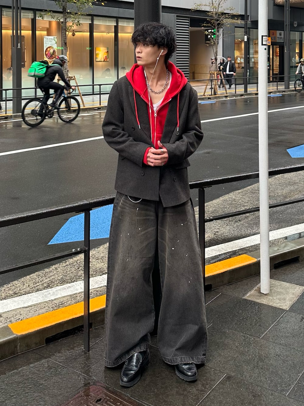 レッド系のパーカー、ブラック系のデニムパンツ、ブラック系のローファーを着用したメンズの秋コーディネートの2枚目の写真