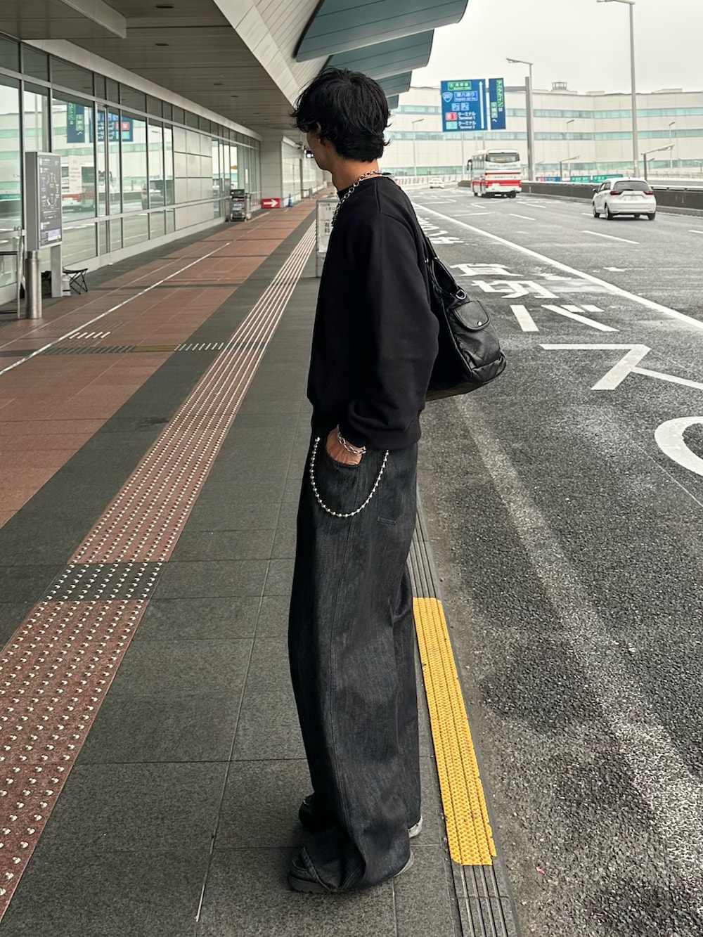 ブラック系のデニムパンツ、ブラック系のスウェット、ブラック系のローファーを着用したメンズの秋コーディネートの3枚目の写真