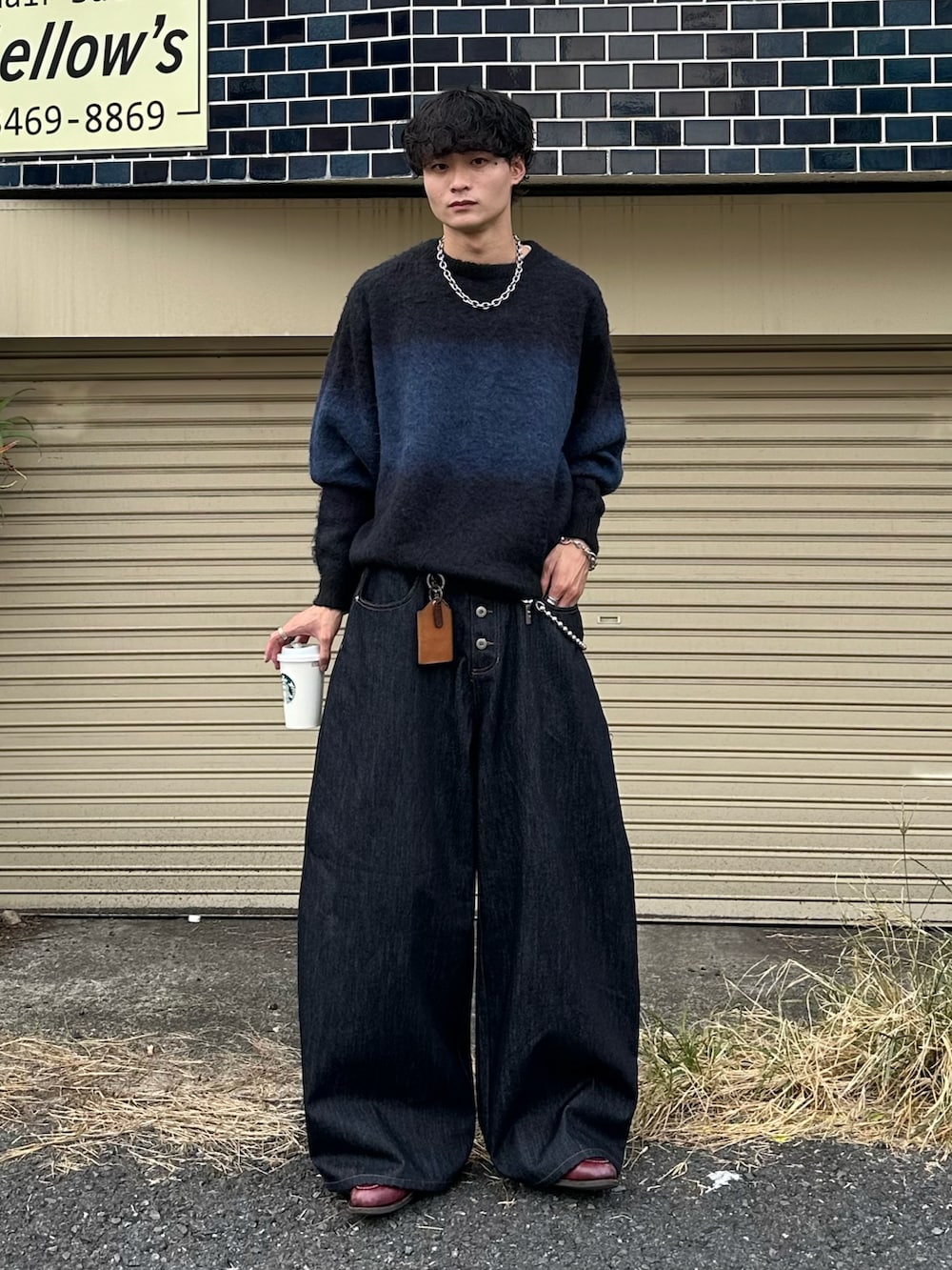 ブラック系のニット/セーター、ブルー系のデニムパンツ、レッド系のローファーを着用したメンズの秋コーディネートの3枚目の写真