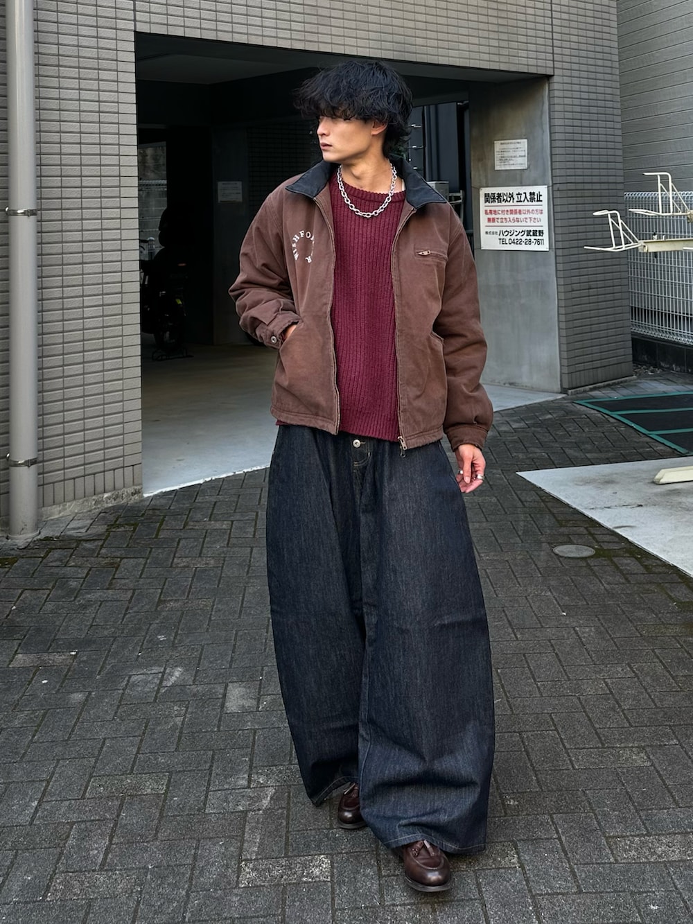 レッド系のニット/セーター、ブラウン系のブルゾン、ブルー系のデニムパンツを着用したメンズの冬コーディネートの2枚目の写真