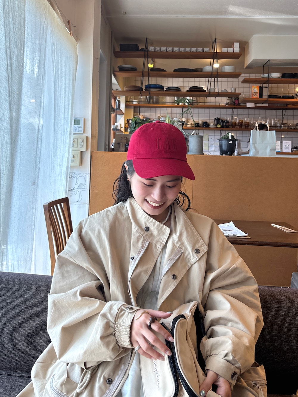 ベージュ系のジャケット/アウター、ベージュ系のボディバッグ/ウエストポーチ、レッド系のキャップを着用したレディースの春コーディネートの3枚目の写真