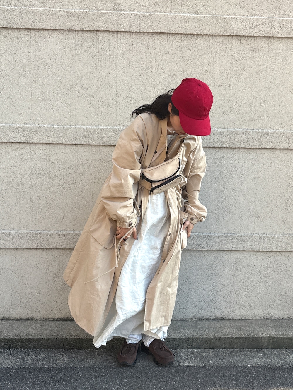 ベージュ系のジャケット/アウター、ベージュ系のボディバッグ/ウエストポーチ、レッド系のキャップを着用したレディースの春コーディネートの2枚目の写真