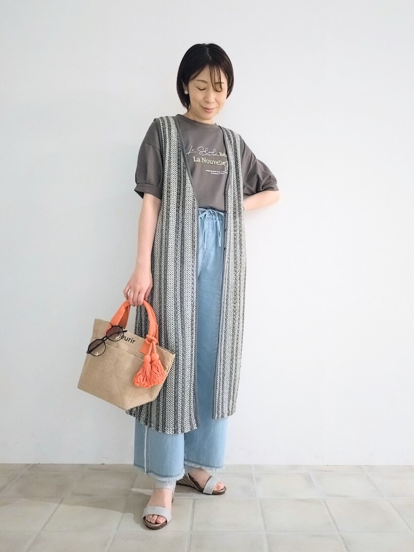 グレー系のTシャツ/カットソー、グレー系のベスト、ブルー系のデニムパンツを着用したレディースの春コーディネートの4枚目の写真