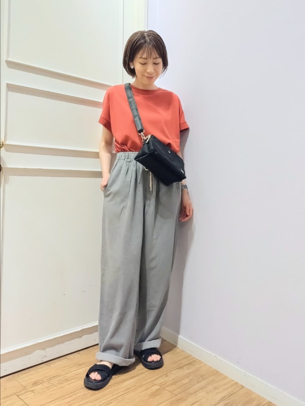 レッド系のTシャツ/カットソー、ブラック系のショルダーバッグ、グレー系のその他パンツを着用したレディースの夏コーディネートの2枚目の写真