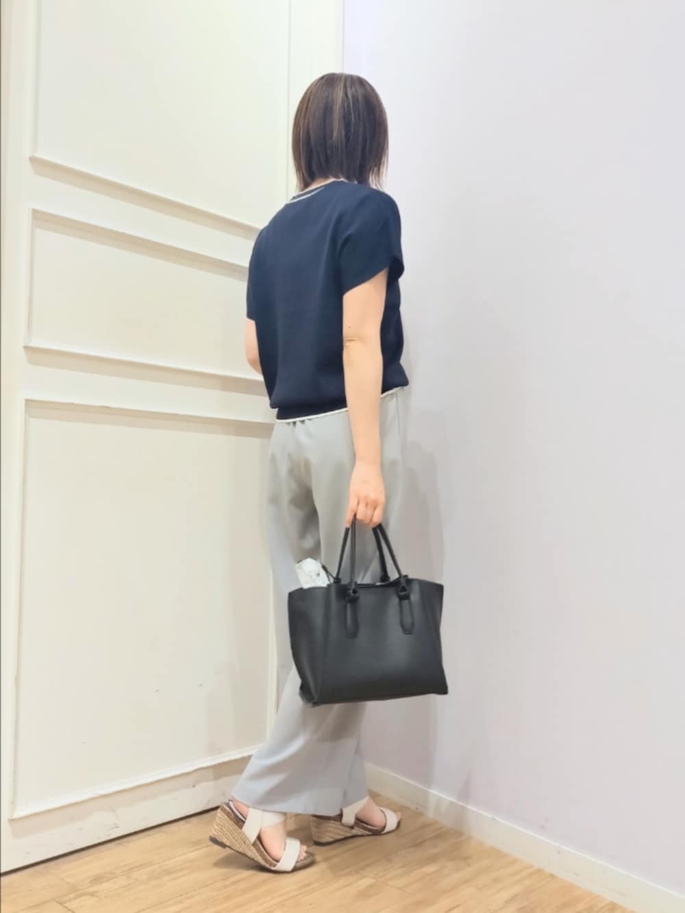 ブルー系のニット/セーター、グレー系のその他パンツ、ブラック系のトートバッグを着用したレディースの春コーディネートの3枚目の写真