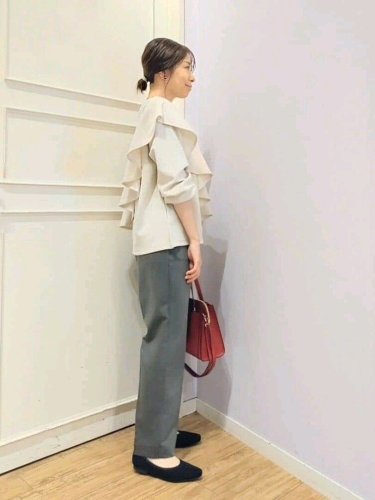 ベージュ系のTシャツ/カットソー、グレー系のその他パンツ、レッド系のトートバッグを着用したレディースの冬コーディネートの2枚目の写真