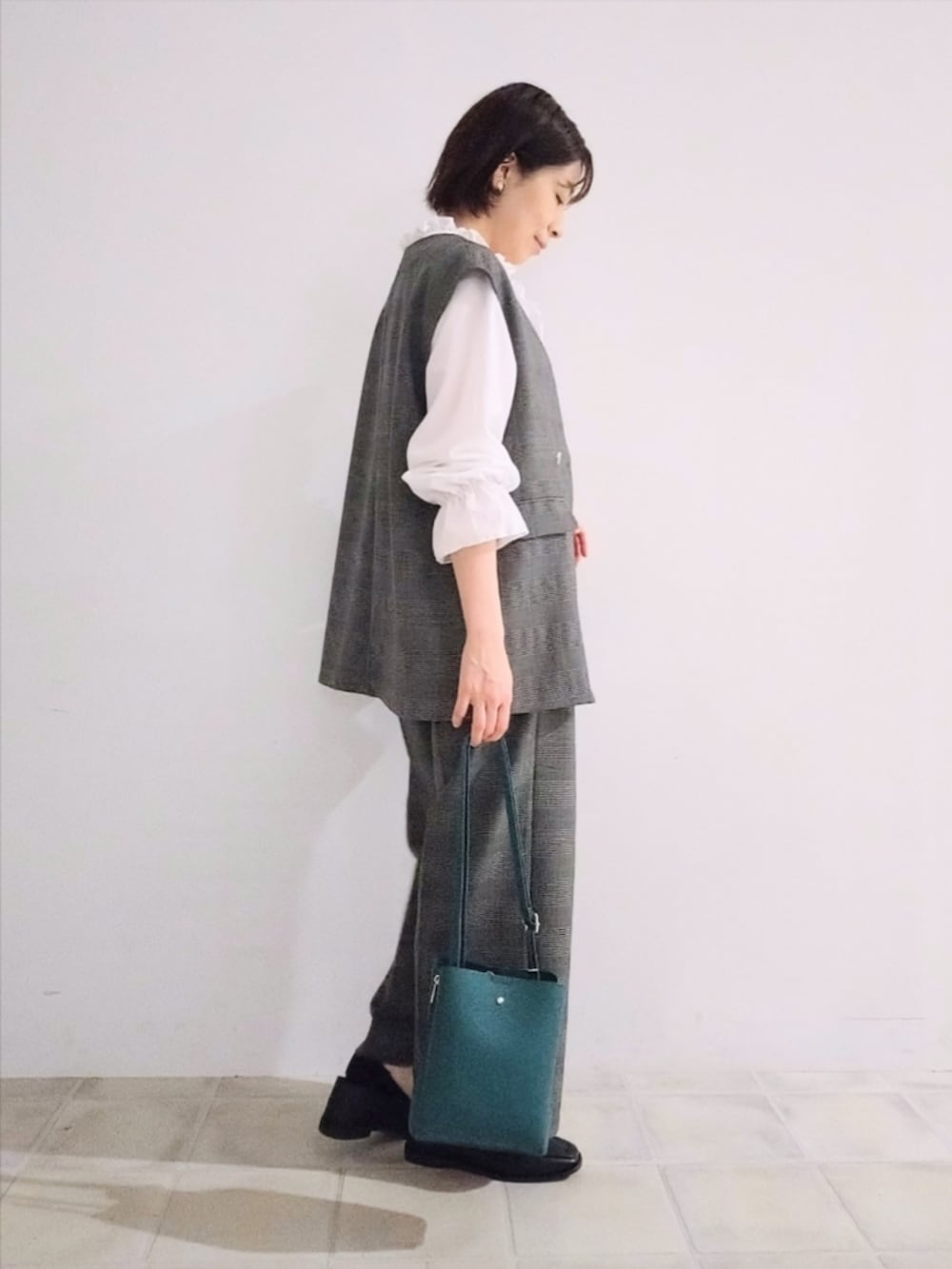 グレー系のベスト、ホワイト系のシャツ/ブラウス、グレー系のその他パンツを着用したレディースの秋コーディネートの2枚目の写真