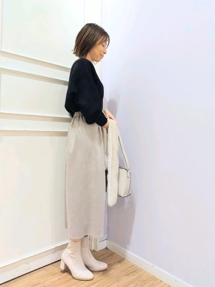ブラック系のニット/セーター、グレー系のショルダーバッグ、ホワイト系のブーツを着用したレディースの冬コーディネートの2枚目の写真