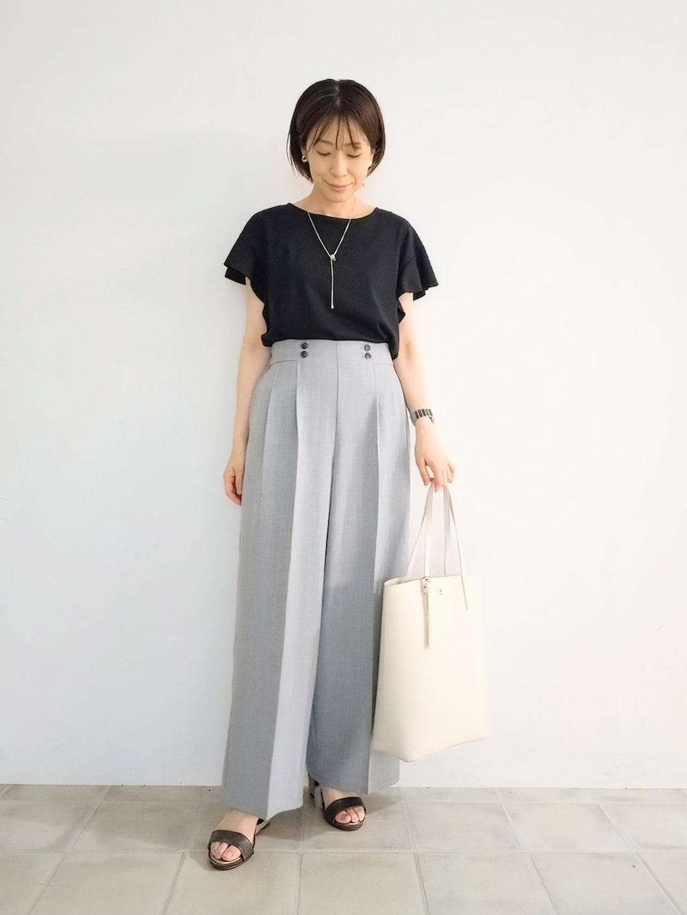 ブラック系のTシャツ/カットソー、グレー系のその他パンツ、ホワイト系のトートバッグを着用したレディースの夏コーディネートの4枚目の写真