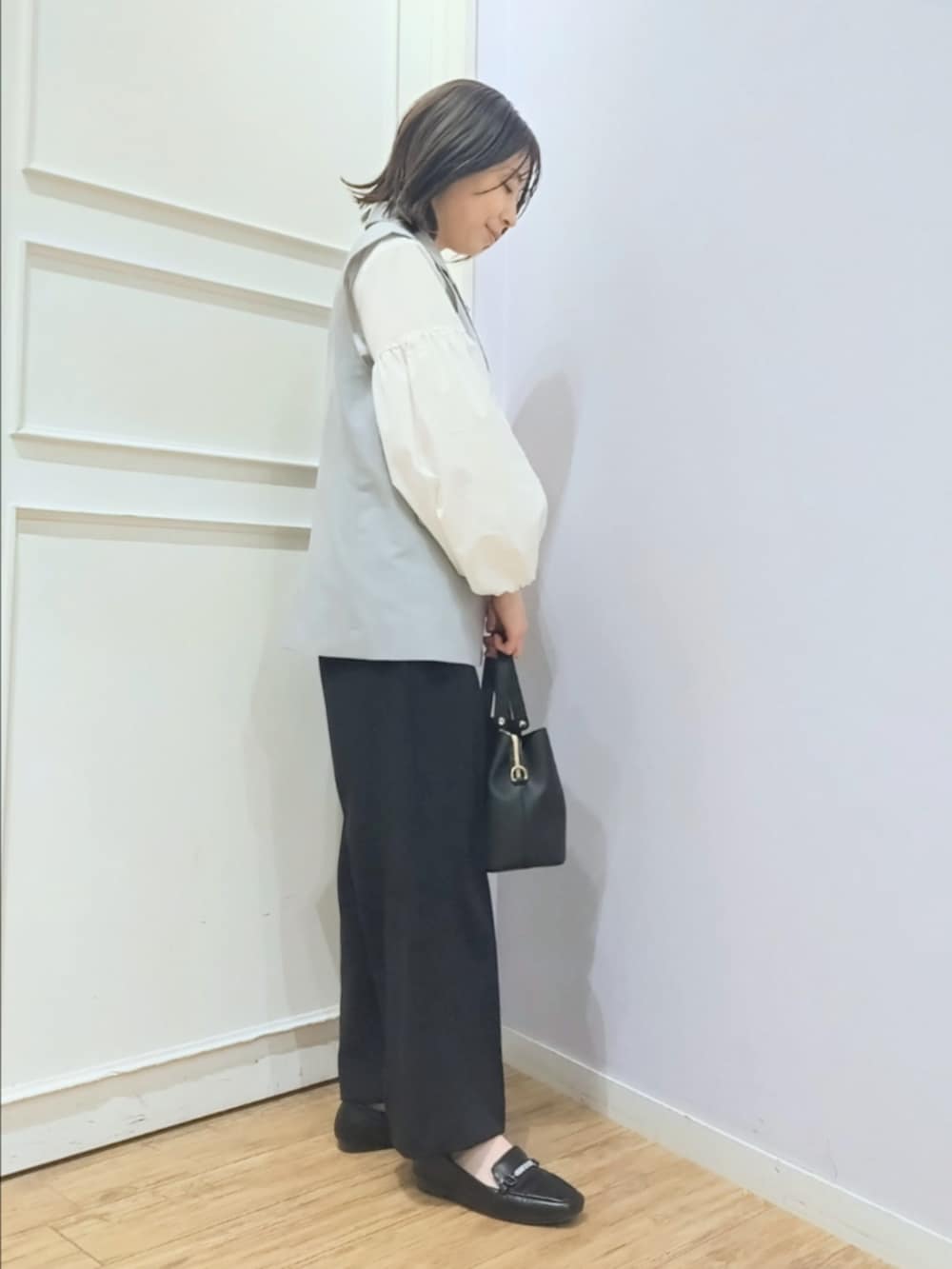 グレー系のベスト、ホワイト系のシャツ/ブラウス、ブラック系のその他パンツを着用したレディースの冬コーディネートの2枚目の写真