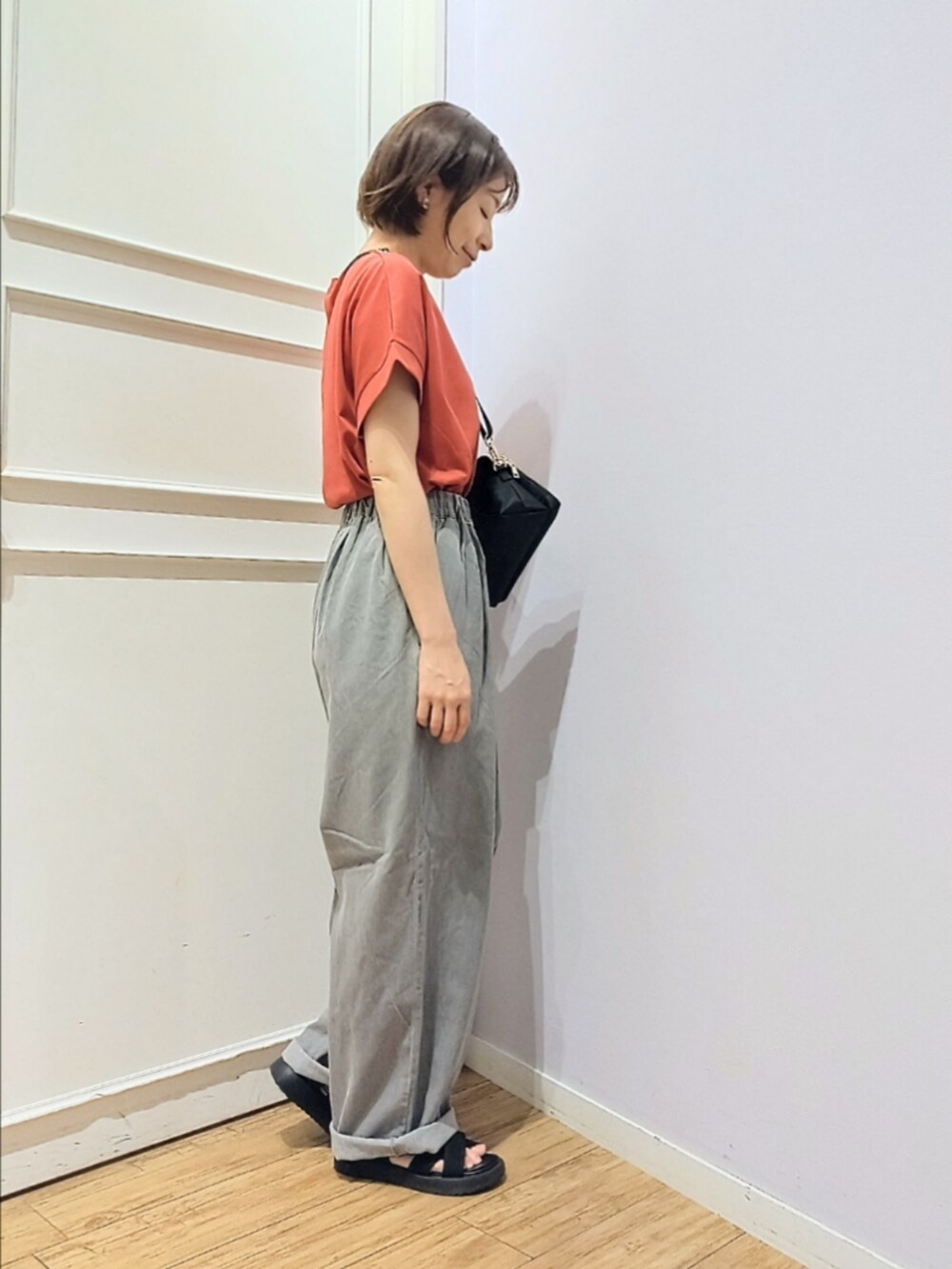 レッド系のTシャツ/カットソー、ブラック系のショルダーバッグ、グレー系のその他パンツを着用したレディースの夏コーディネートの3枚目の写真