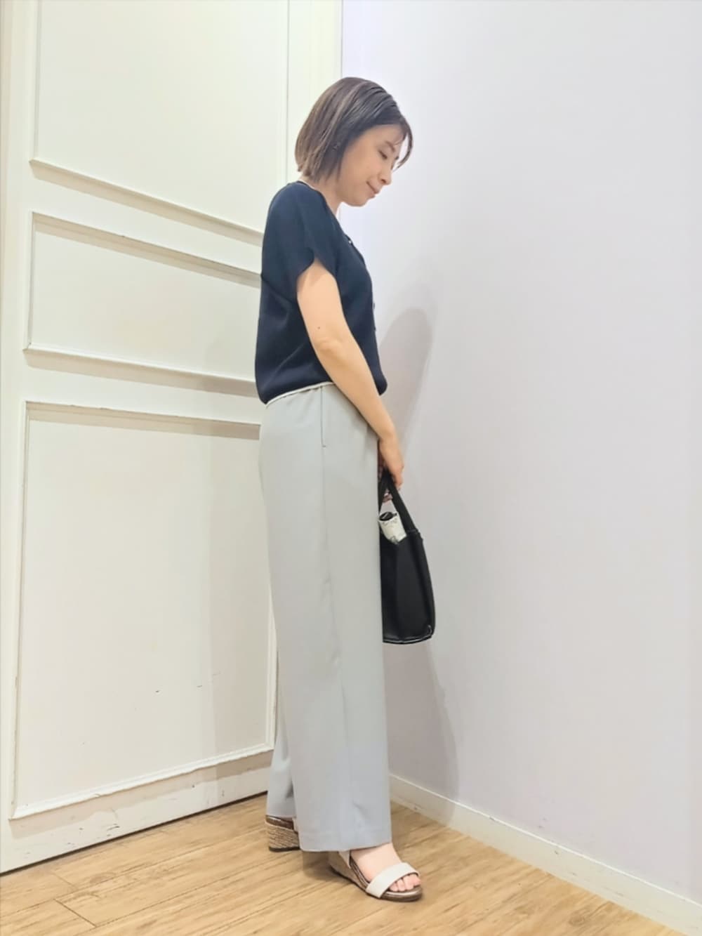 ブルー系のニット/セーター、グレー系のその他パンツ、ブラック系のトートバッグを着用したレディースの春コーディネートの2枚目の写真