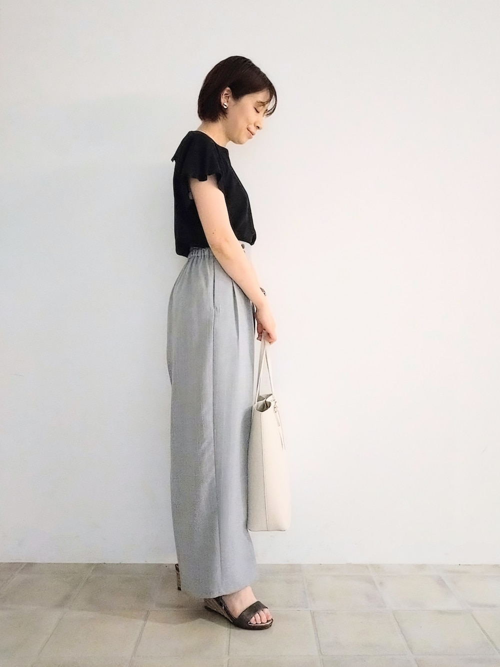 ブラック系のTシャツ/カットソー、グレー系のその他パンツ、ホワイト系のトートバッグを着用したレディースの夏コーディネートの2枚目の写真
