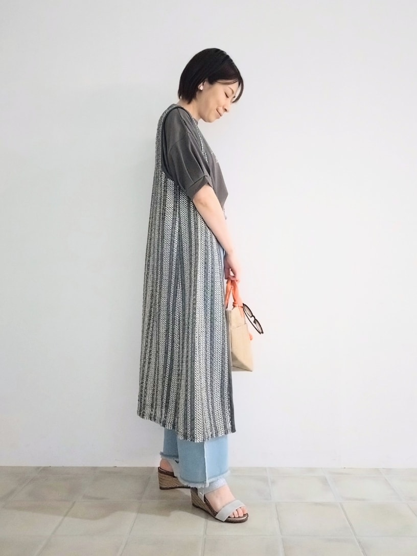 グレー系のTシャツ/カットソー、グレー系のベスト、ブルー系のデニムパンツを着用したレディースの春コーディネートの2枚目の写真