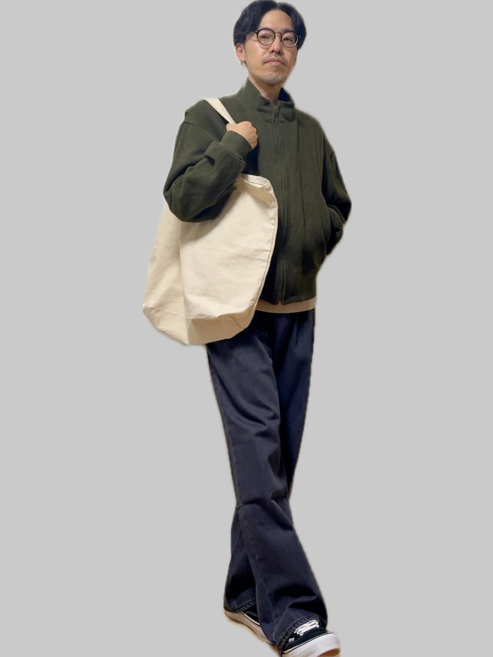 ベージュ系のニット/セーター、グリーン系のミリタリージャケット、ブルー系のデニムパンツを着用したメンズの冬コーディネートの2枚目の写真