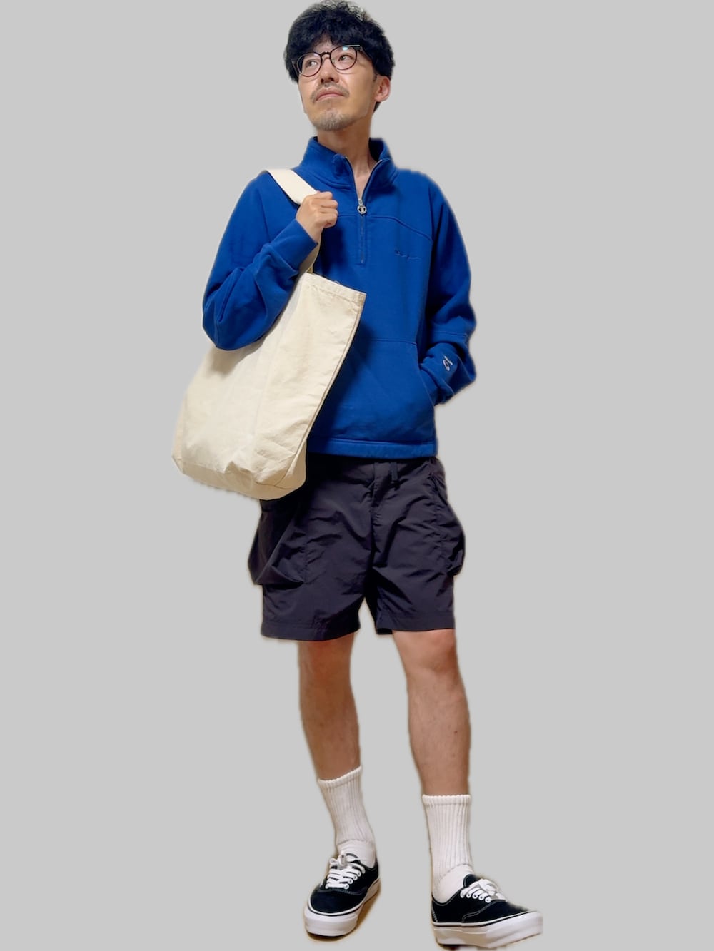 ブラック系のスニーカー、ブラック系のカーゴパンツ、ベージュ系のトートバッグを着用したメンズの秋コーディネートの2枚目の写真