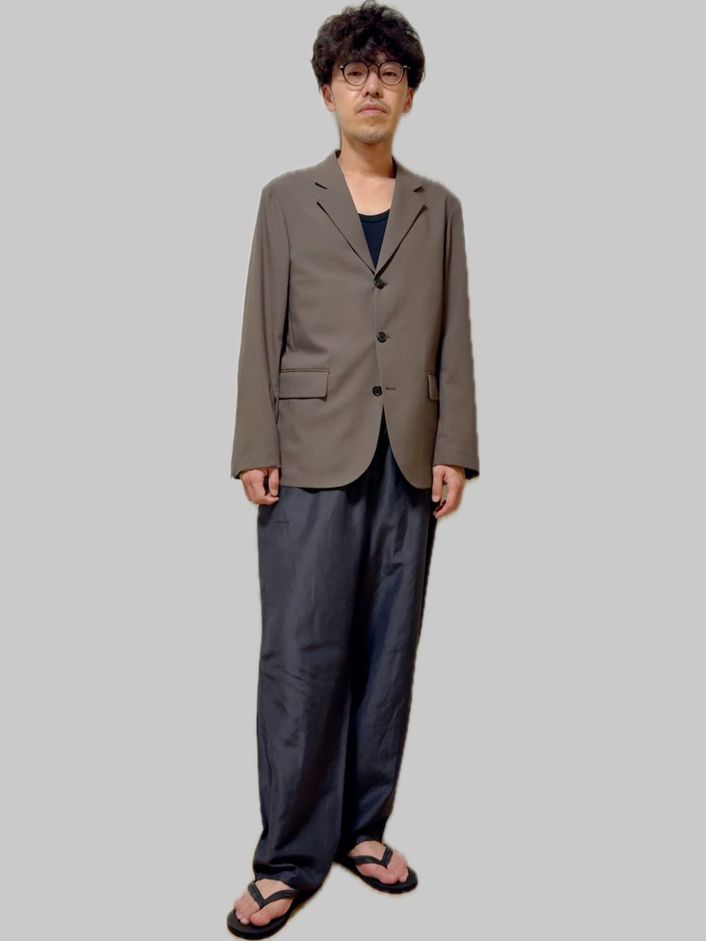 グレー系のテーラードジャケット、グレー系のその他パンツ、ブラック系のサンダルを着用したメンズの秋コーディネートの3枚目の写真