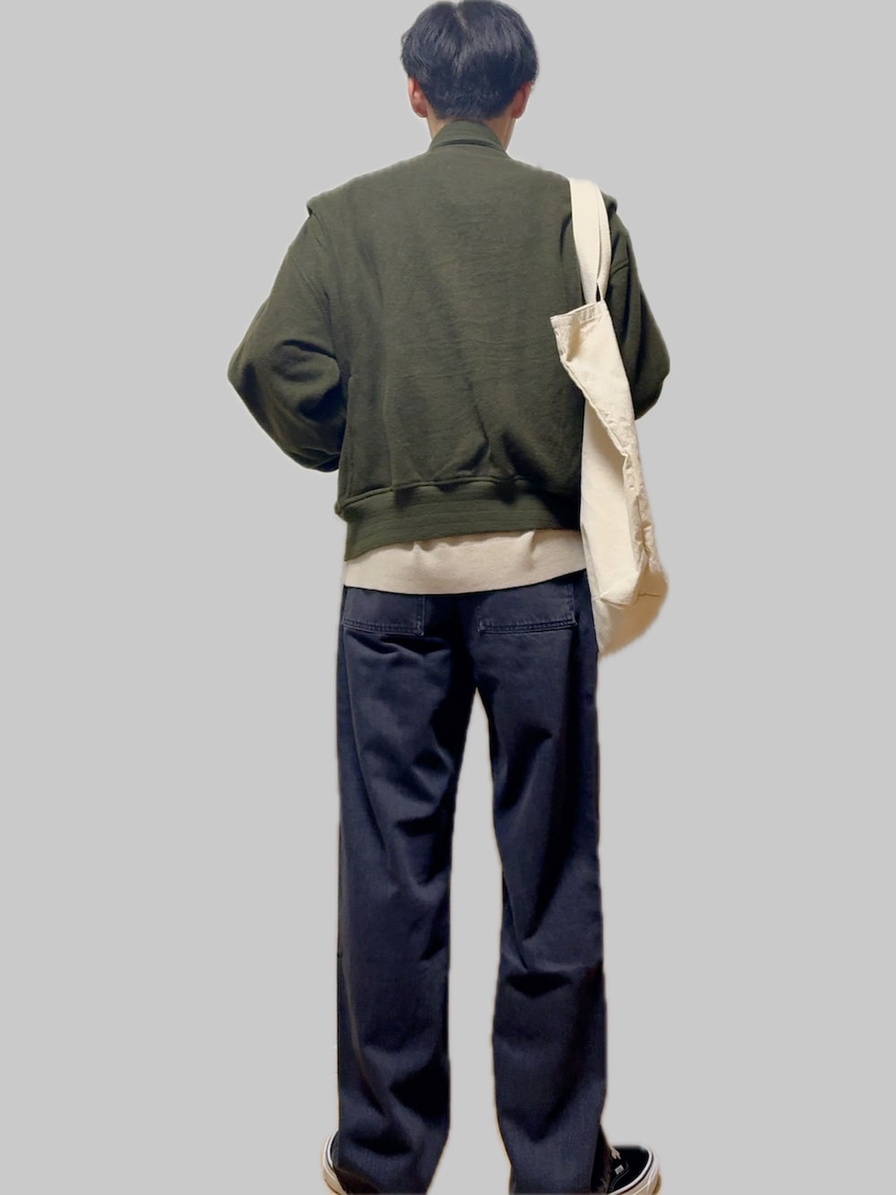 ベージュ系のニット/セーター、グリーン系のミリタリージャケット、ブルー系のデニムパンツを着用したメンズの冬コーディネートの3枚目の写真