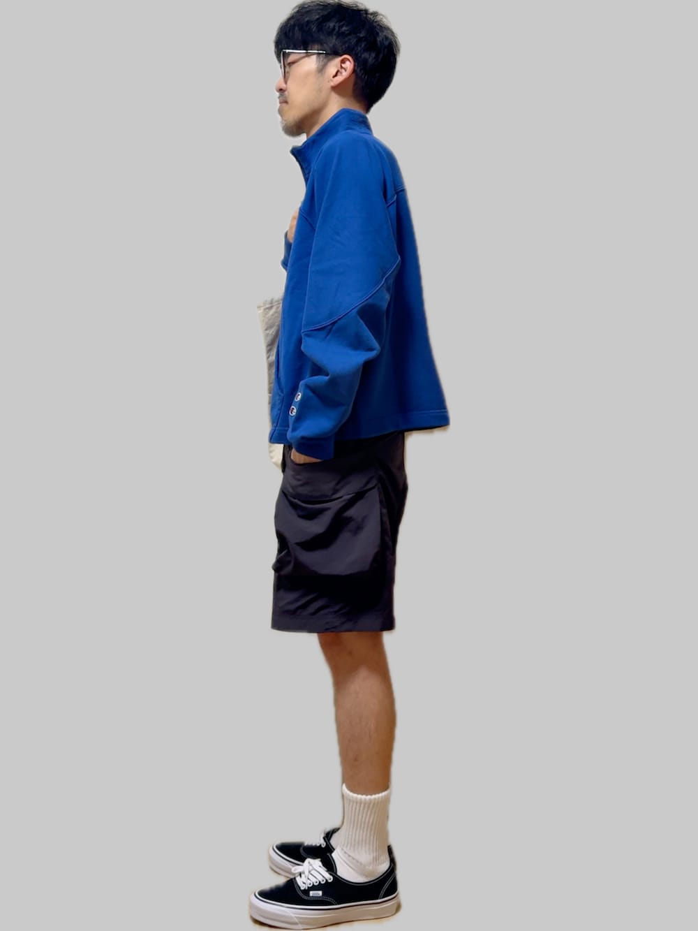 ブラック系のスニーカー、ブラック系のカーゴパンツ、ベージュ系のトートバッグを着用したメンズの秋コーディネートの4枚目の写真