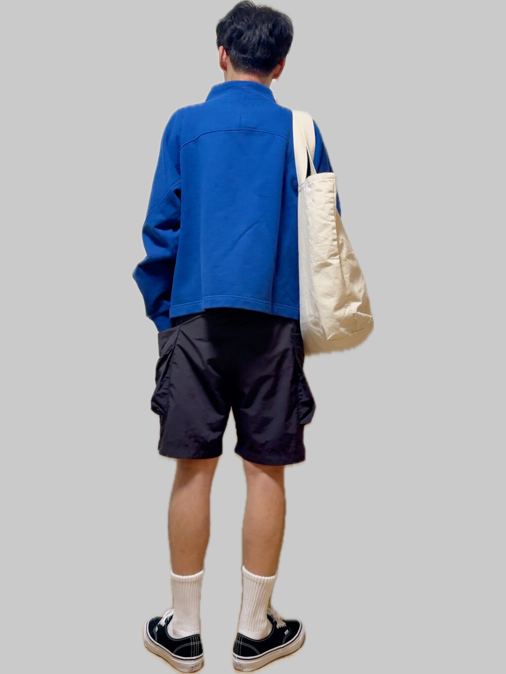 ブラック系のスニーカー、ブラック系のカーゴパンツ、ベージュ系のトートバッグを着用したメンズの秋コーディネートの3枚目の写真