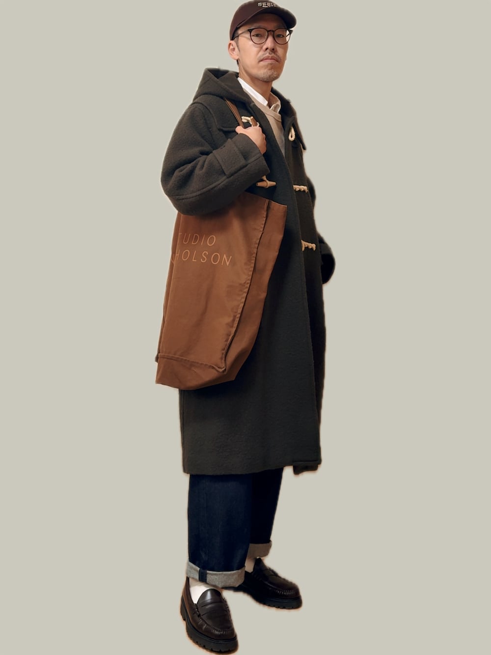 グリーン系のダッフルコート、ブラウン系のトートバッグ、ブルー系のデニムパンツを着用したメンズの冬コーディネートの5枚目の写真