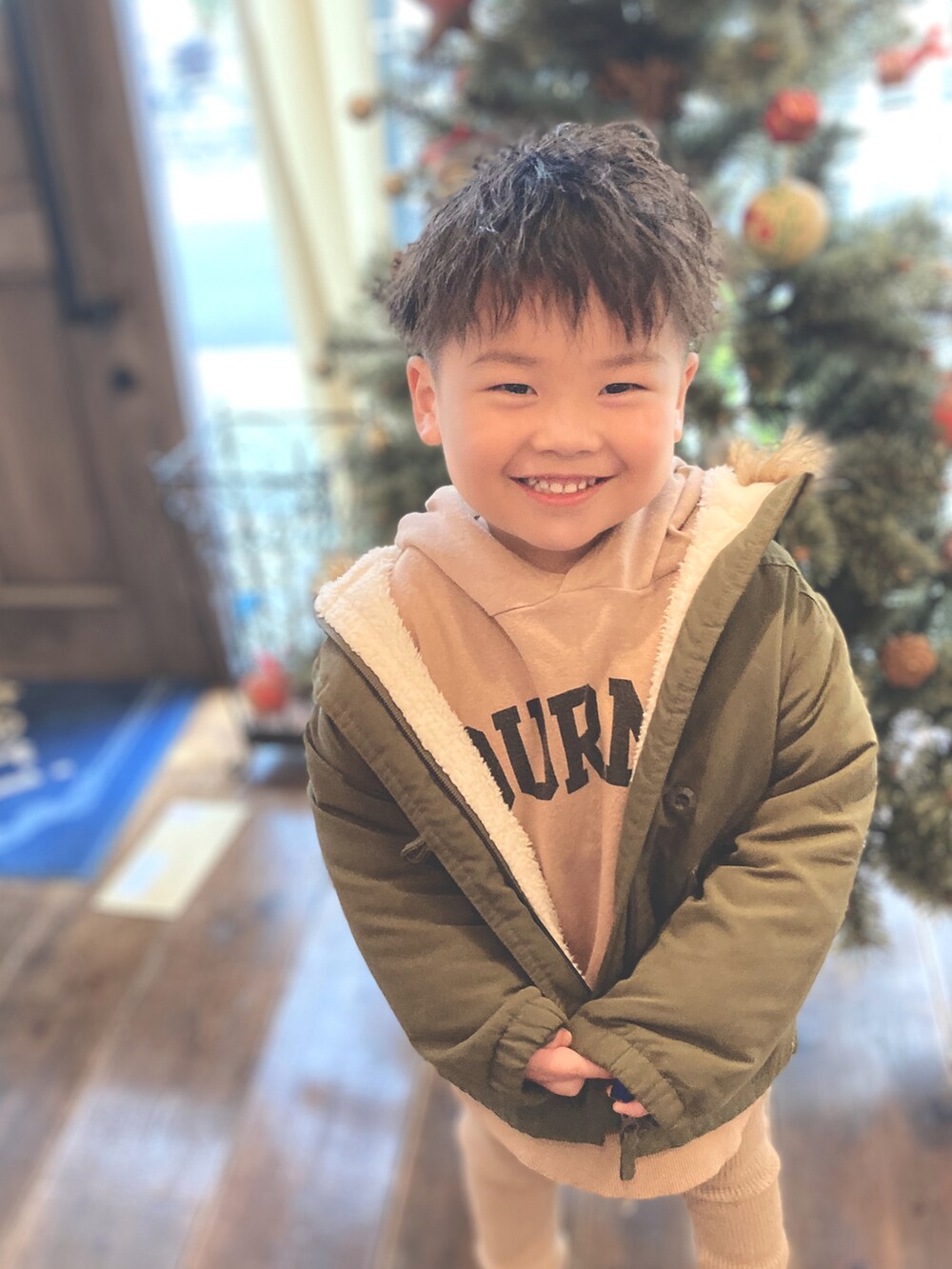 ベージュ系のパーカー、グリーン系のミリタリージャケット、ベージュ系のスラックスを着用したキッズの冬コーディネートの3枚目の写真