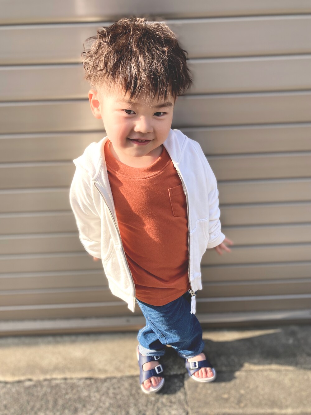 ホワイト系のパーカー、オレンジ系のTシャツ/カットソー、ブルー系のデニムパンツを着用したキッズの春コーディネートの2枚目の写真