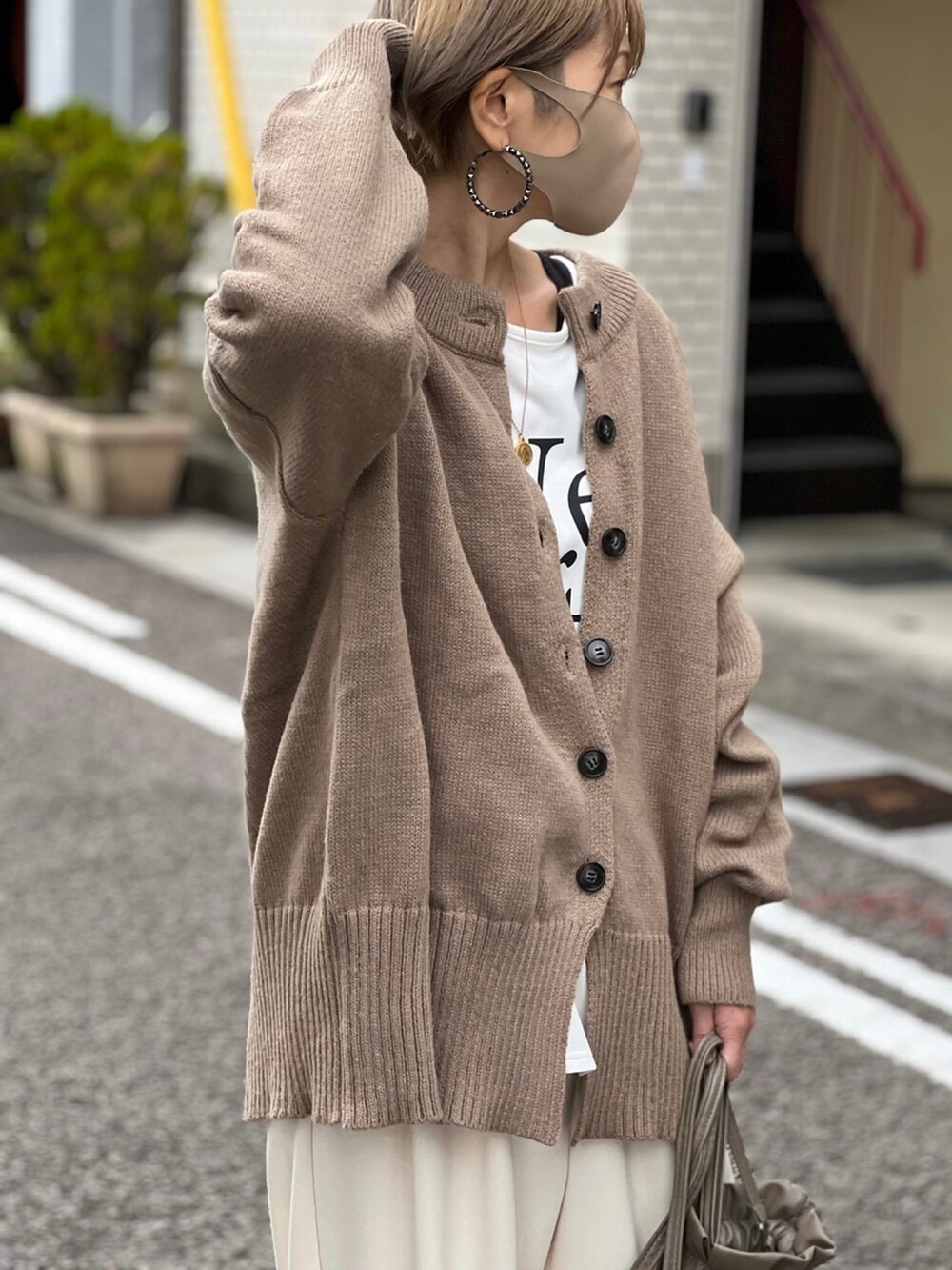 ブラウン系のカーディガン/ボレロ、ブラック系のスニーカー、ホワイト系のTシャツ/カットソーを着用したレディースの冬コーディネートの2枚目の写真