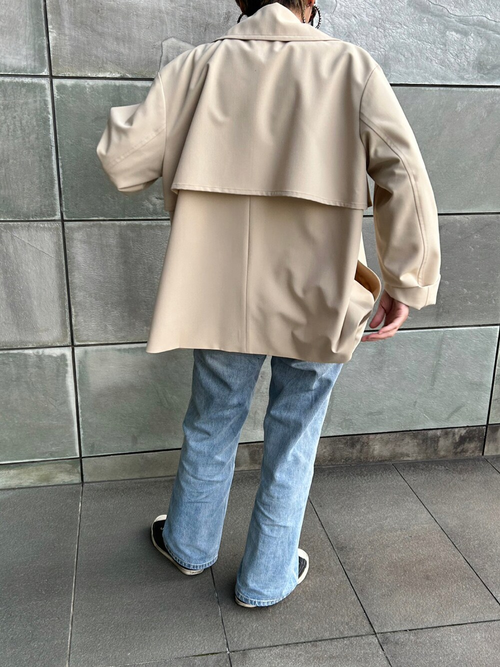 ベージュ系のトレンチコート、ブルー系のデニムパンツ、ブラック系のスニーカーを着用したレディースの春コーディネートの3枚目の写真