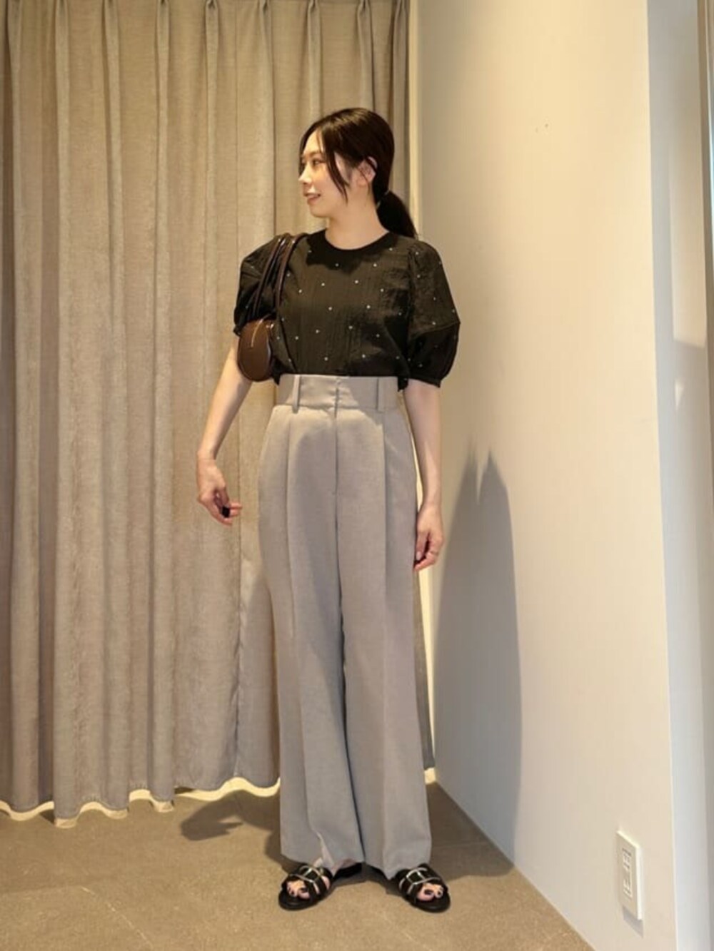 ブラック系のシャツ/ブラウス、ベージュ系のスラックスを着用したレディースの夏コーディネートの2枚目の写真