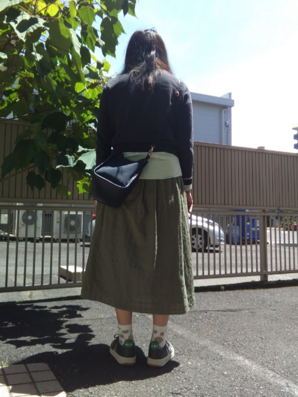 グレー系のニット/セーター、グリーン系のTシャツ/カットソー、グリーン系のスニーカーを着用したレディースの春コーディネートの2枚目の写真