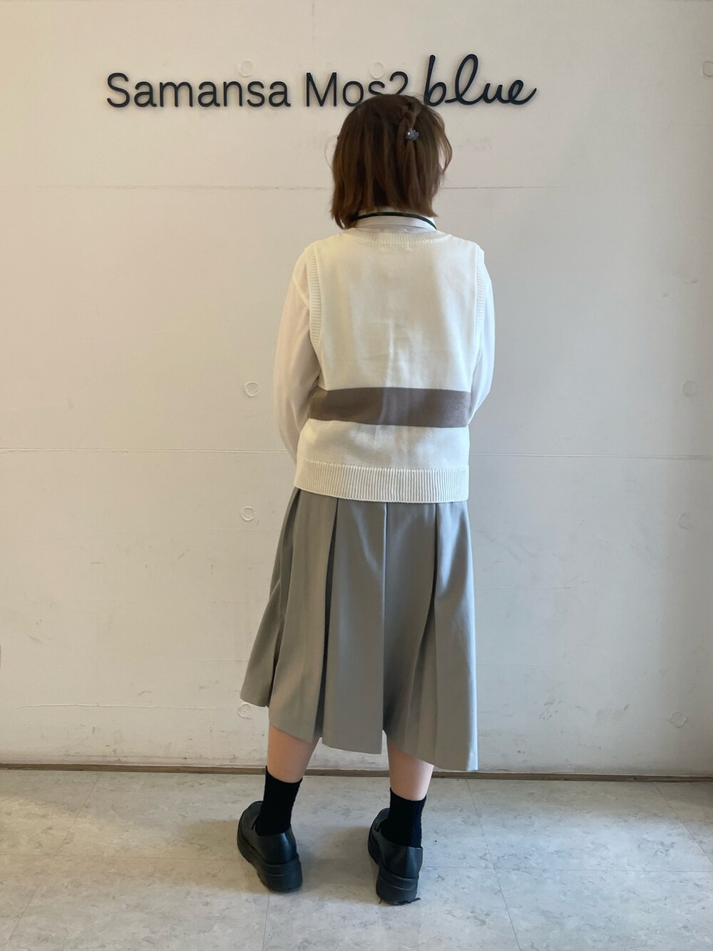 ホワイト系のベスト、ホワイト系のTシャツ/カットソー、グレー系のスカートを着用したレディースの春コーディネートの2枚目の写真