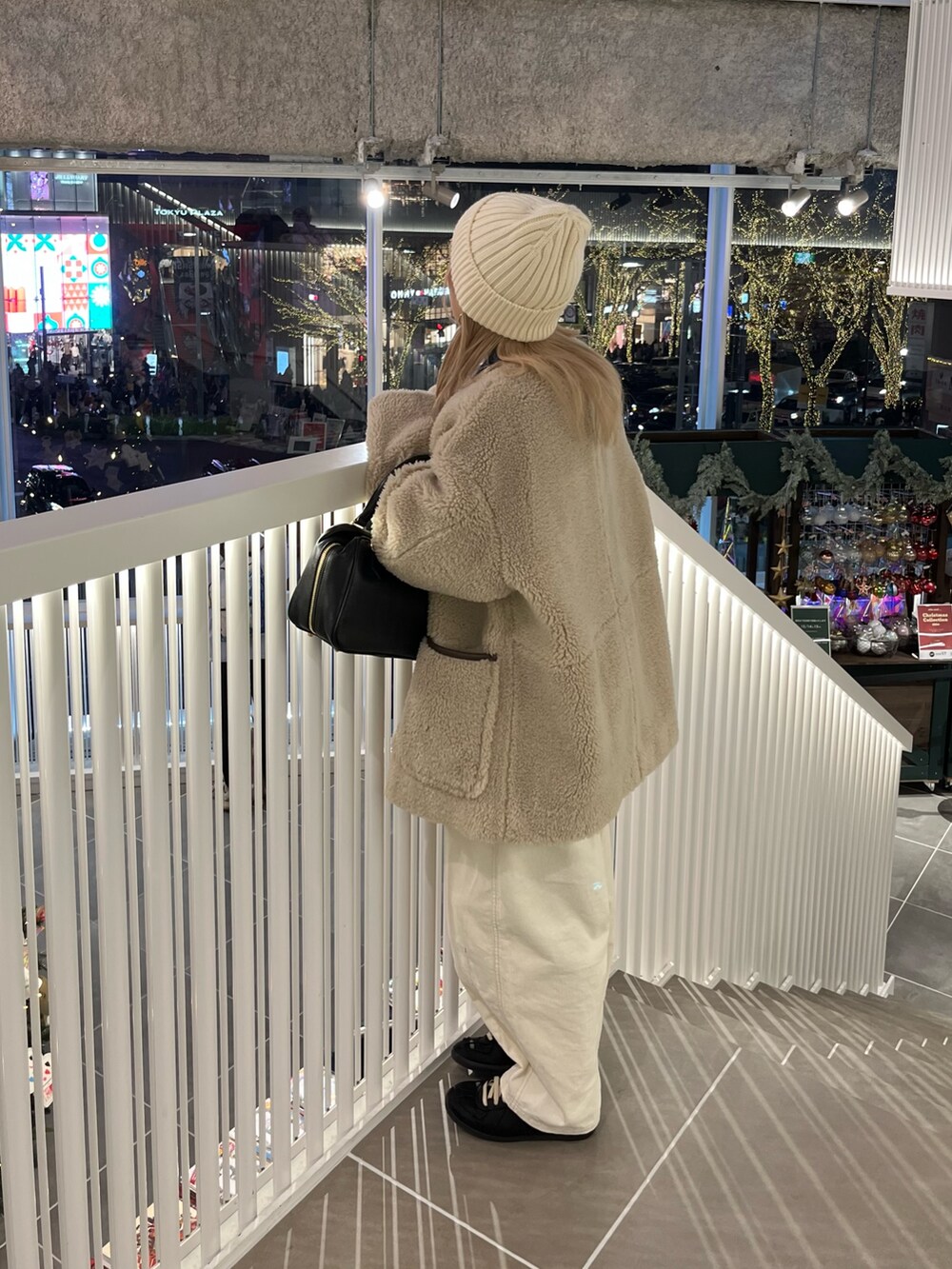 ベージュ系のノーカラーコート、ホワイト系のその他パンツ、ブラック系のハンドバッグを着用したレディースの冬コーディネートの5枚目の写真