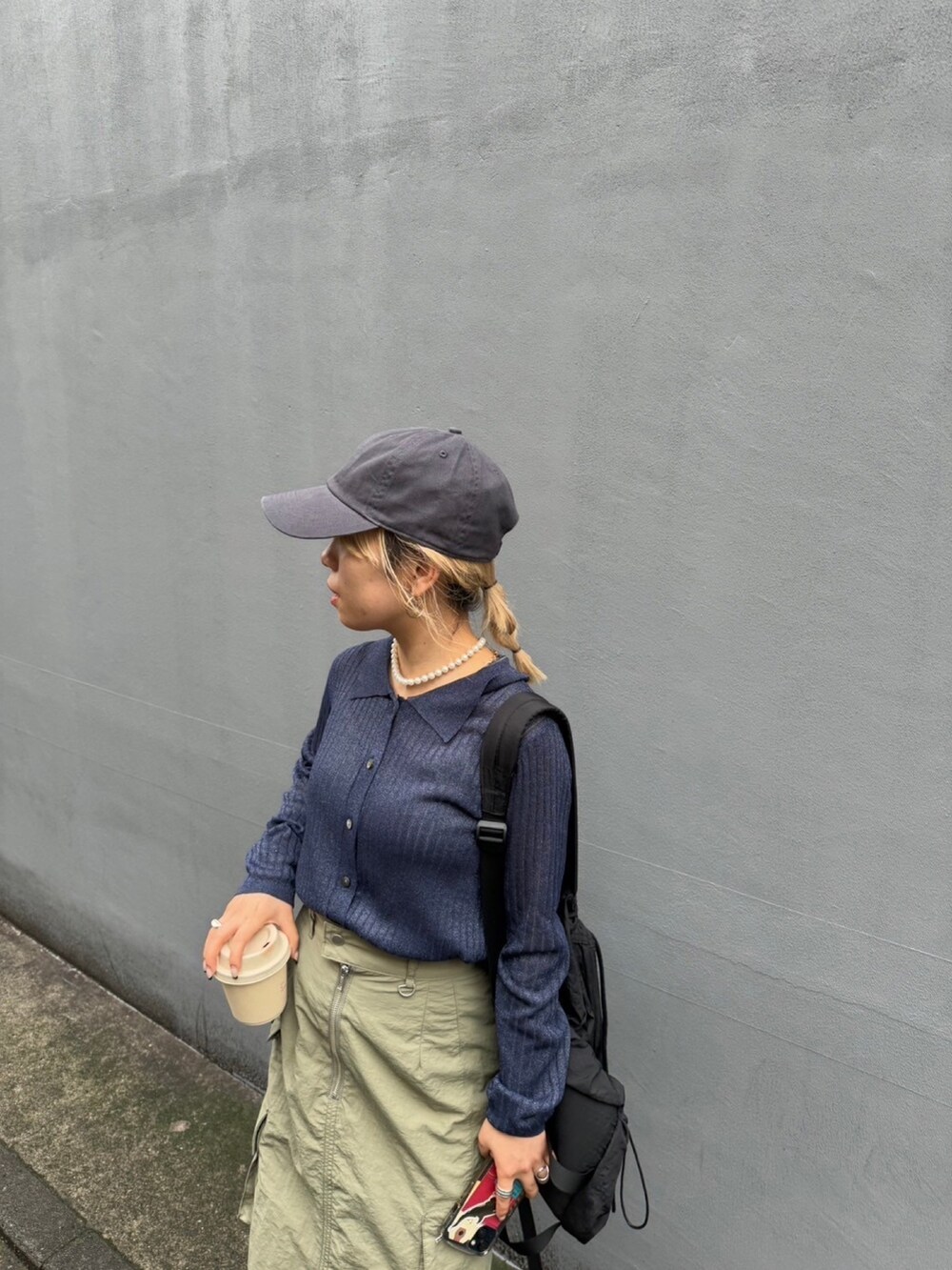 ブルー系のニット/セーター、グリーン系のスカート、グレー系のキャップを着用したレディースの春コーディネートの3枚目の写真